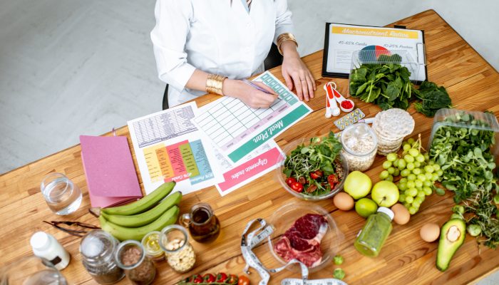Dietitian writing a diet plan, view from above on the table with different healthy products and drawings on the topic of healthy eating